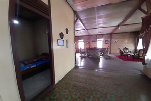 A spacious room with a high ceiling, a bed with a blue mattress, a wooden door, and a red carpet. - OYO Homes 91248 Desa Wisata Banding Agung Danau Ra (Banding Agung)