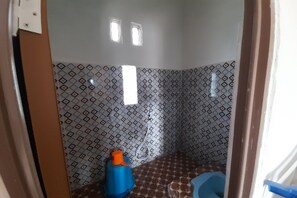 A bathroom with patterned tiles, a blue toilet, and a blue container. - OYO Homes 91248 Desa Wisata Banding Agung Danau Ra (Banding Agung)