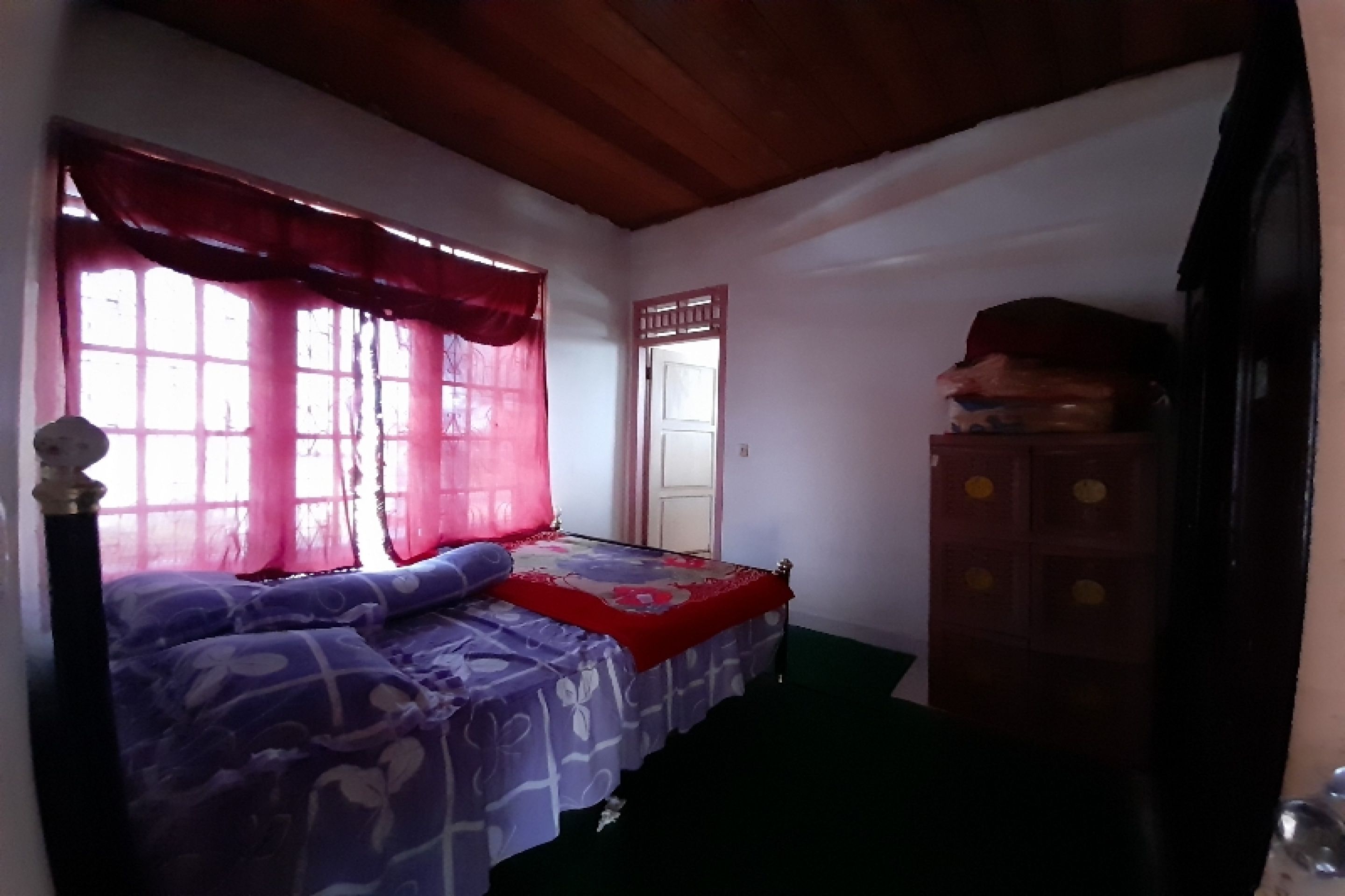 A bedroom with a bed, a wardrobe, and a window with curtains.