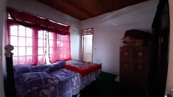 A bedroom with a bed, a wardrobe, and a window with curtains.
