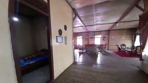 Una habitación amplia con techo alto, suelo estampado y una zona de estar con sillas y sofá.