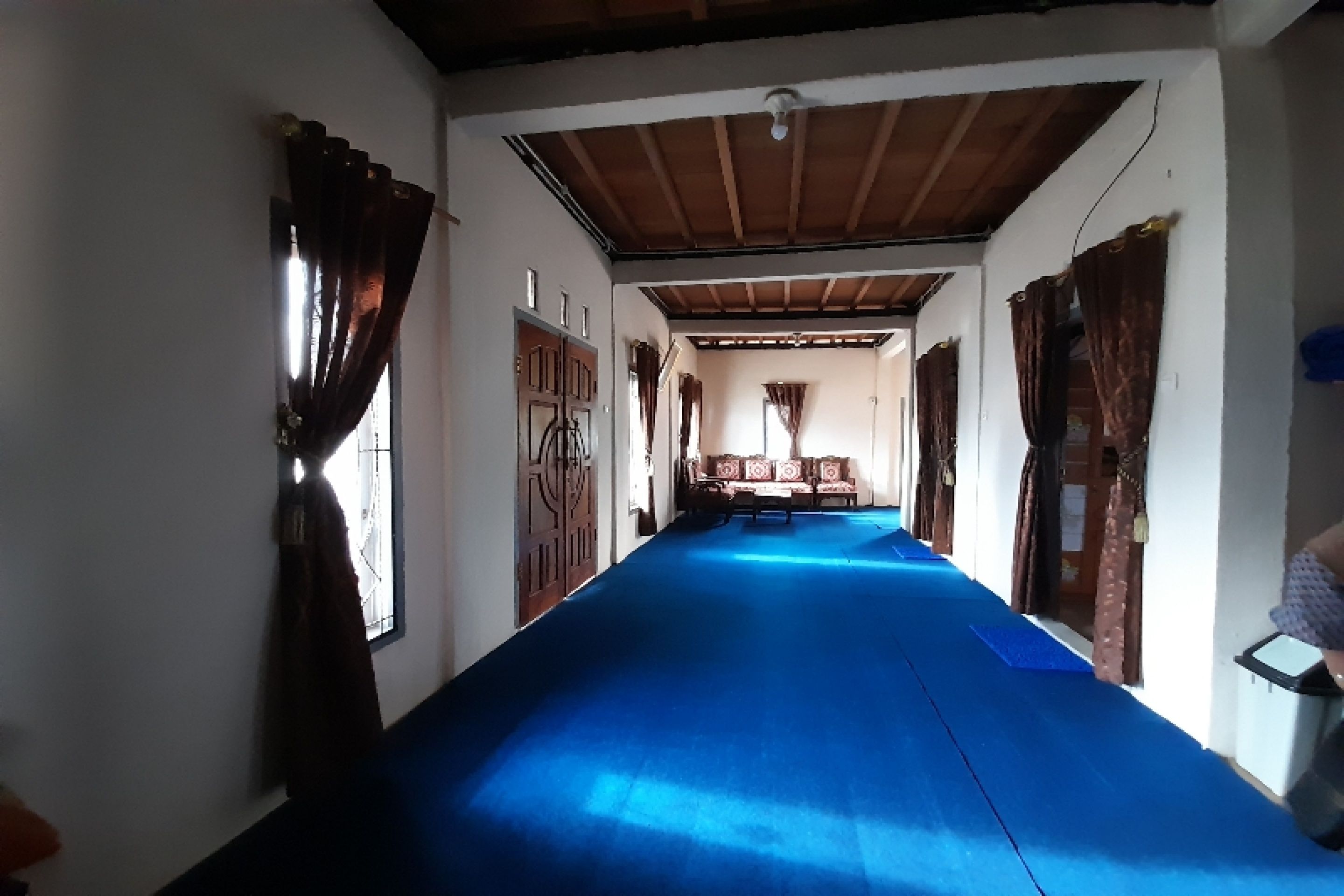 A hallway with a blue carpet, wooden doors, and a bench in the center.