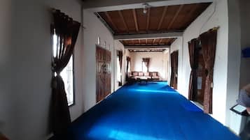 A hallway with a blue carpet, wooden doors, and a bench in the center.