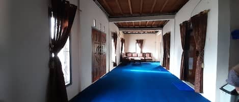 A hallway with a blue carpet, wooden doors, and a bench in the center.