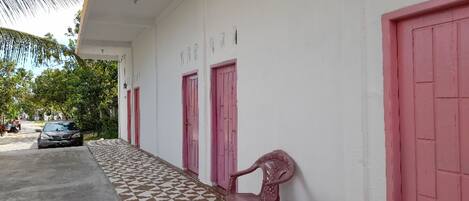 A building with a tiled walkway, pink doors, and a parked car.