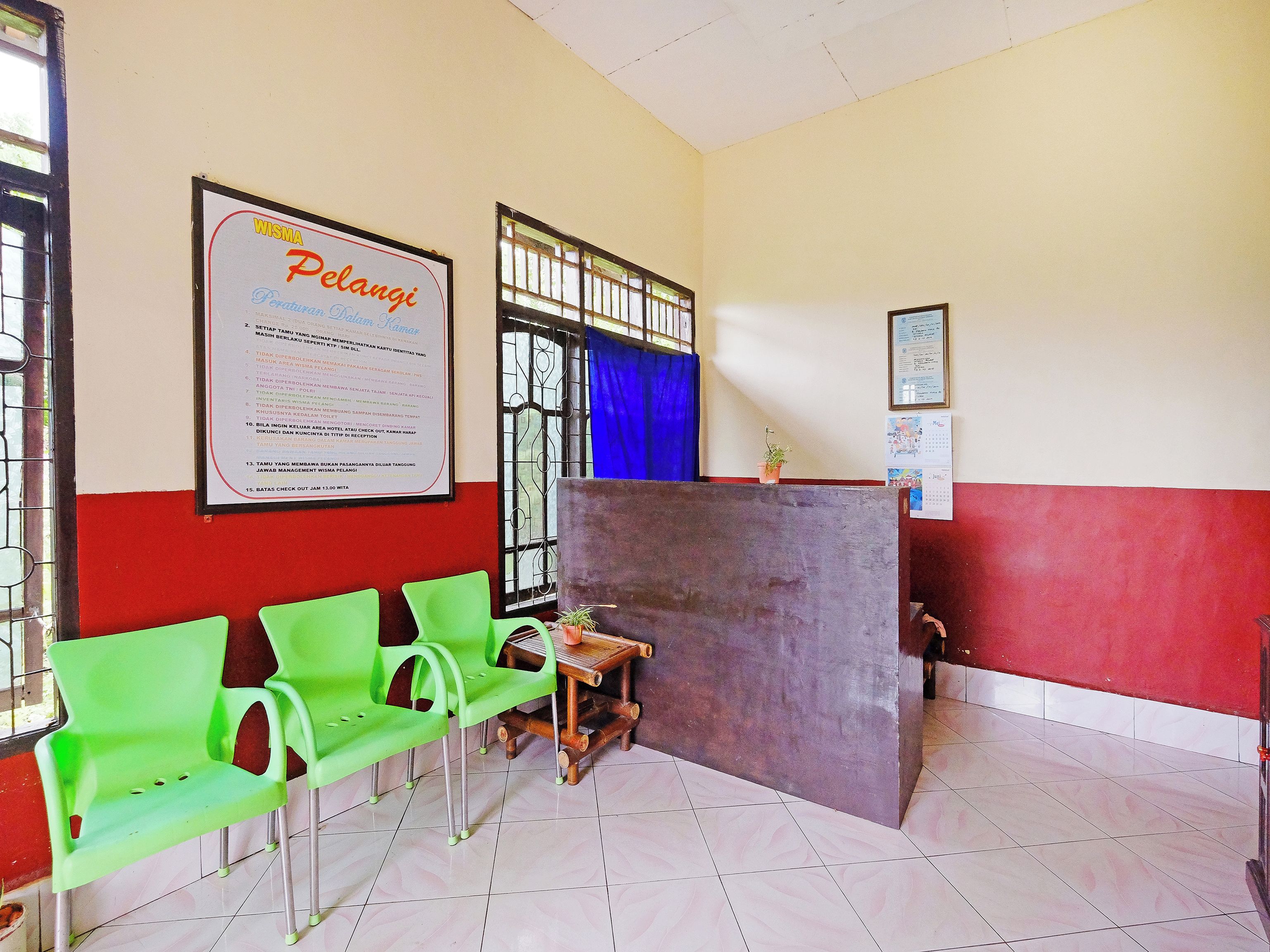A waiting area with green chairs, a wooden table, and a bulletin board with a notice.