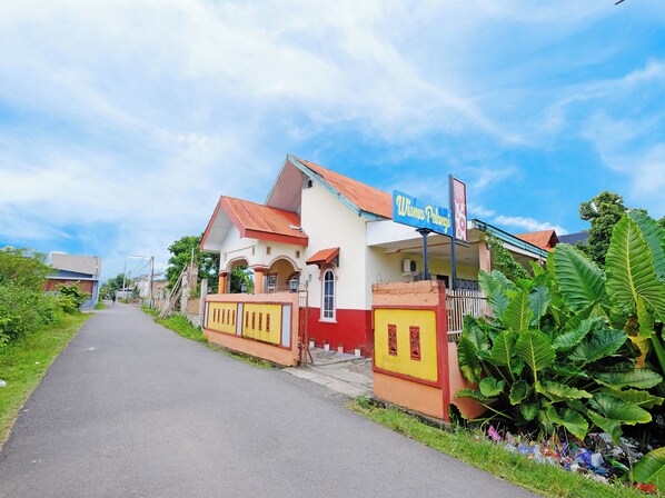 A two-story building with a sign reading "Wisma Pelangi".