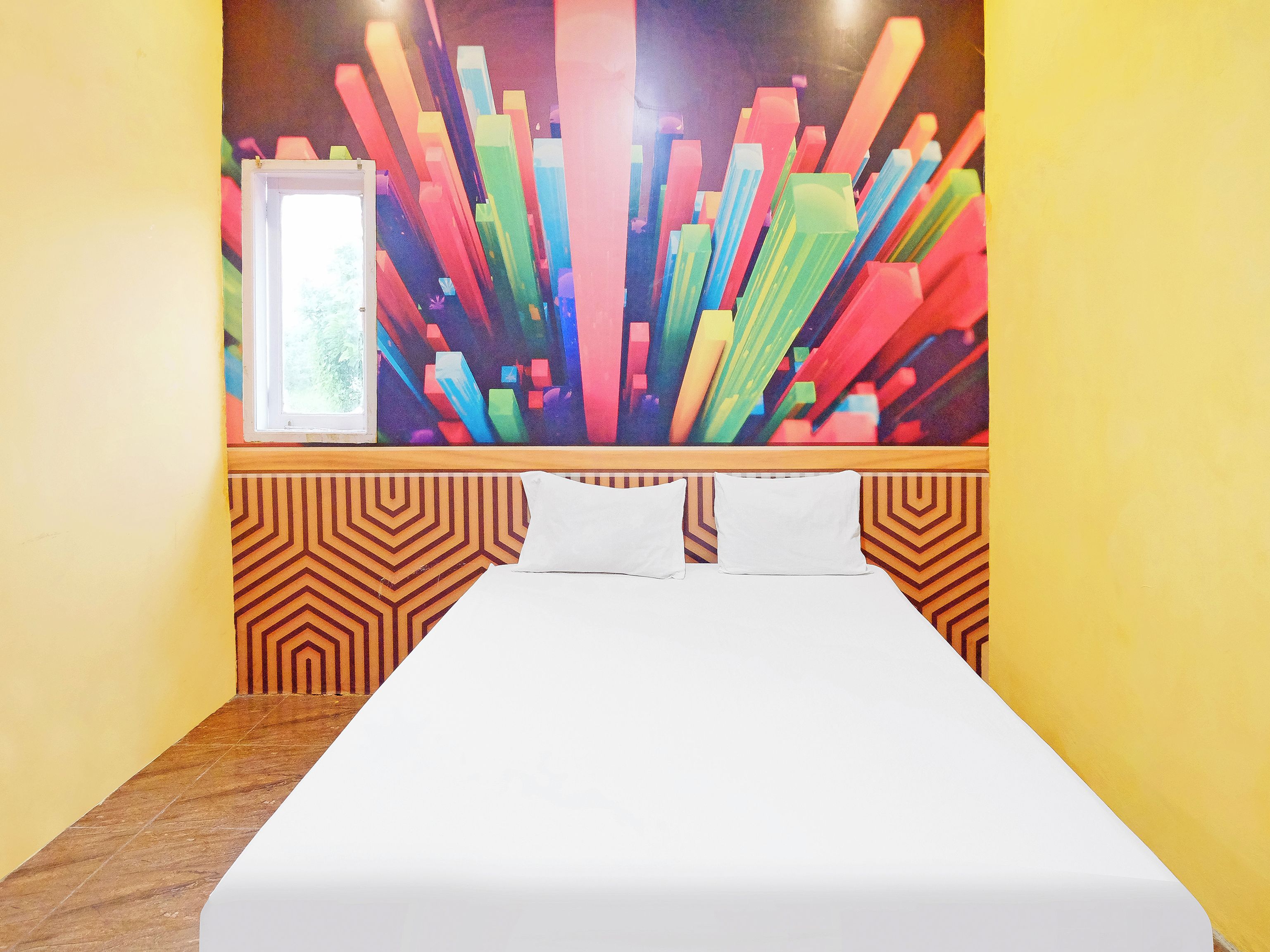 A hotel room with a bed, a window, and a colorful abstract painting on the wall.