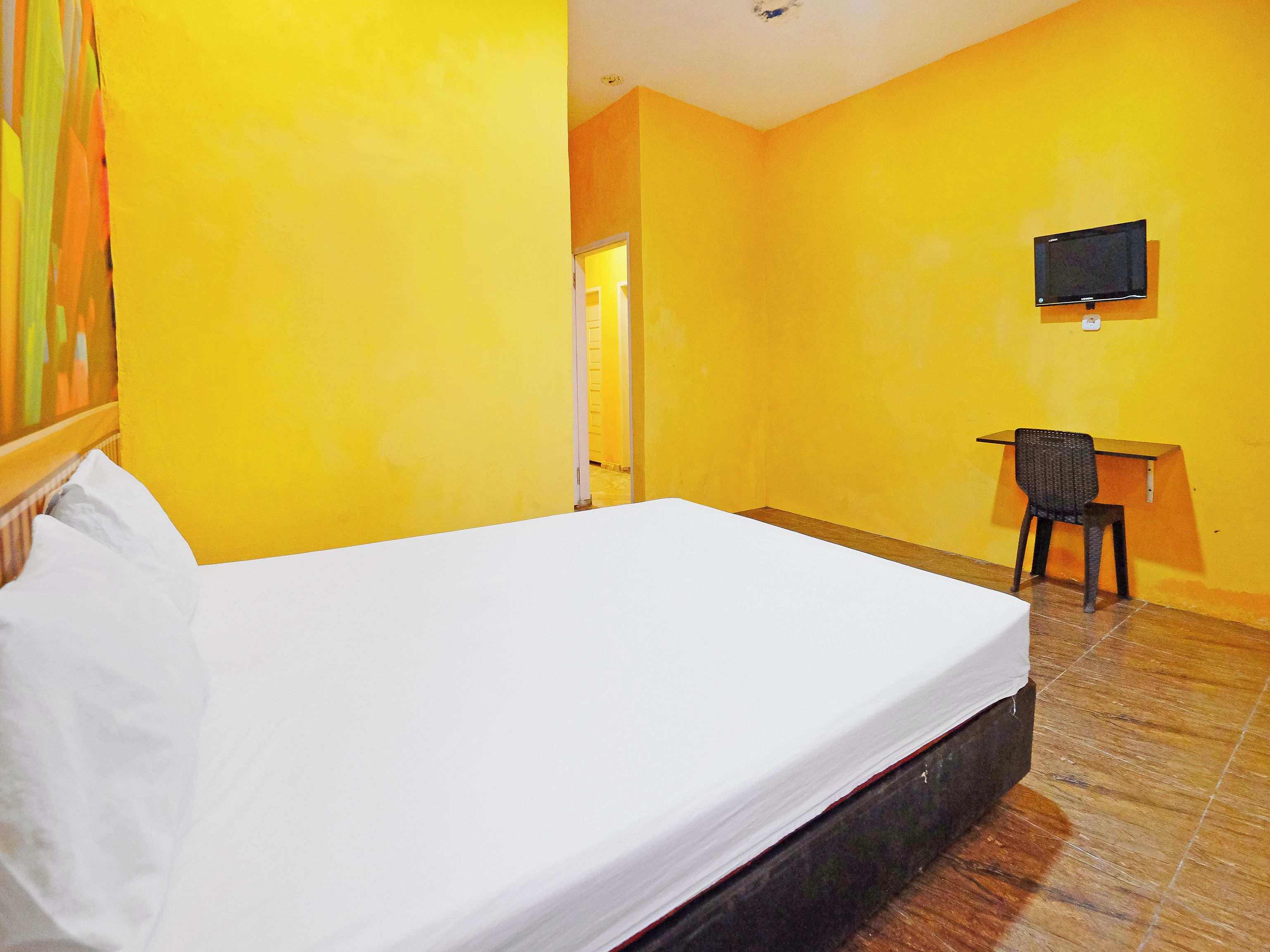A hotel room with a single bed, a desk, and a chair.