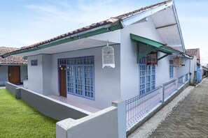 Una casa con techo inclinado, un balcón y una jaula de pájaros colgada de la cornisa.