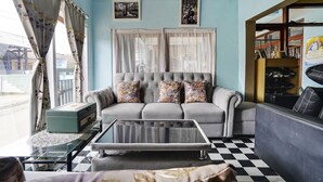 A living room with a sofa, a glass coffee table, and a checkered floor. - OYO 91011 Eco Tourism Desa Cibodas Areng 1 Syariah (Lembang)