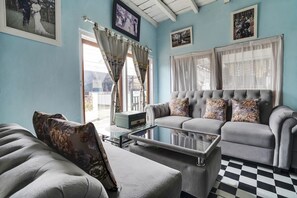 A living room with a grey sofa, a glass coffee table, and a checkered floor.