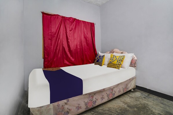 A bed with a white mattress, red curtains, and patterned pillows.