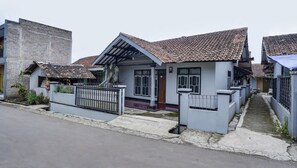 A residential building with a tiled roof, a gated entrance, and a small garden area.