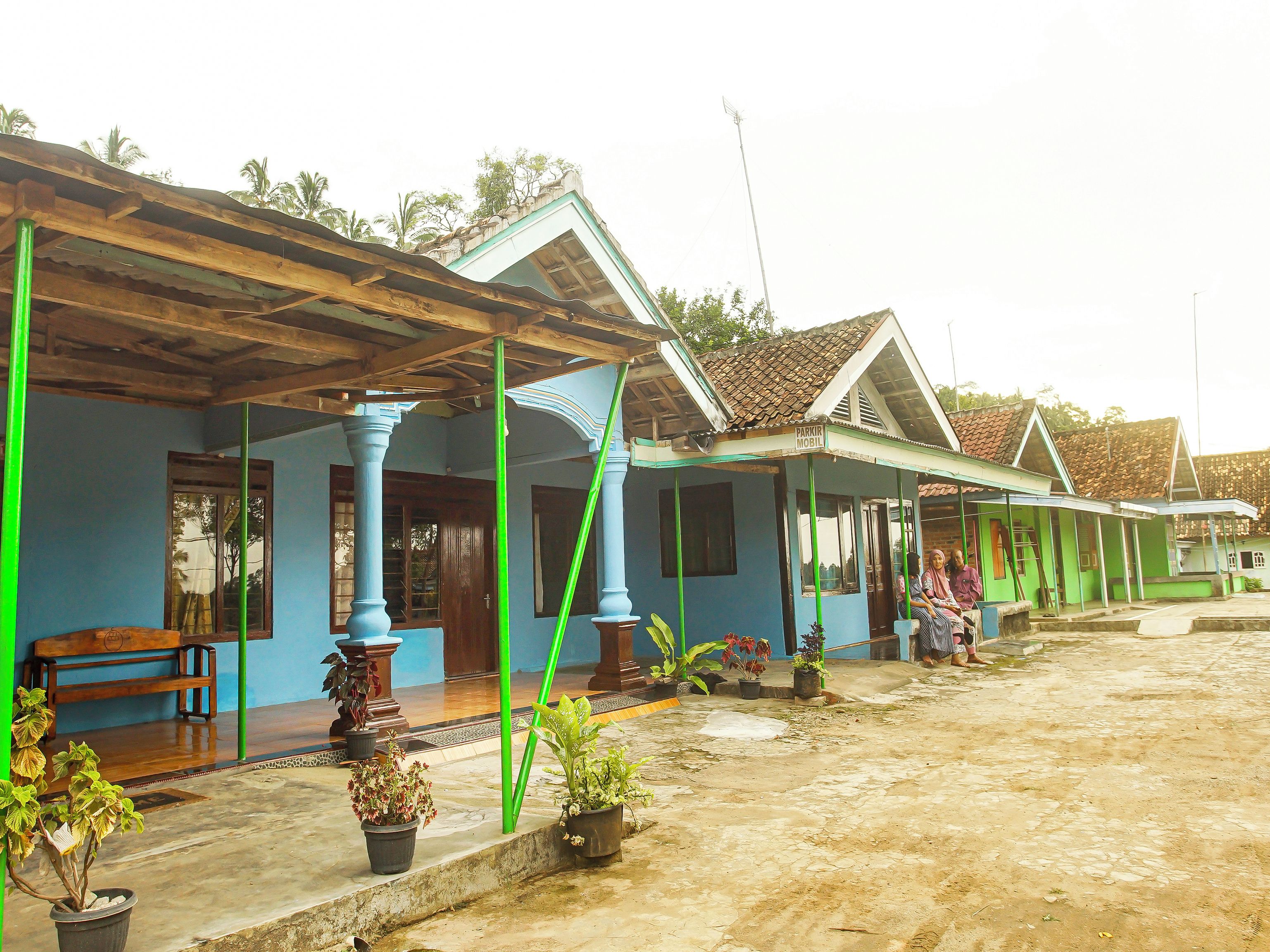 A residential area with blue houses, a wooden bench, and potted plants.