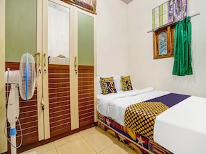 A bedroom with a bed, a fan, a wardrobe, and a window with curtains. - OYO 91089 Desa Wisata Air Terjun Way Kalam Syariah (Kalianda)
