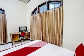 A room with a bed, a desk, a chair, and a television.