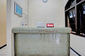 Un comptoir d’accueil avec un ordinateur portable et une enseigne indiquant « Hôtel OYO ».