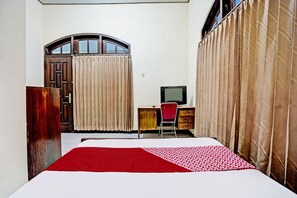 Une chambre à coucher comprenant un lit, un bureau avec une chaise, une télévision et une armoire.
