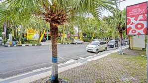 A street with palm trees, a road, and a hotel sign. - OYO 91198 Hotel Mahkota 2 Lamongan (Lamongan)