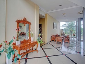 A spacious lobby with a large mirror, ornate wooden furniture, and potted plants. - OYO 90947 Hotel Sarbini (Menggala)