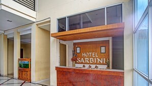 Un comptoir d’accueil d’hôtel avec une enseigne indiquant « HÔTEL SARBINI ».