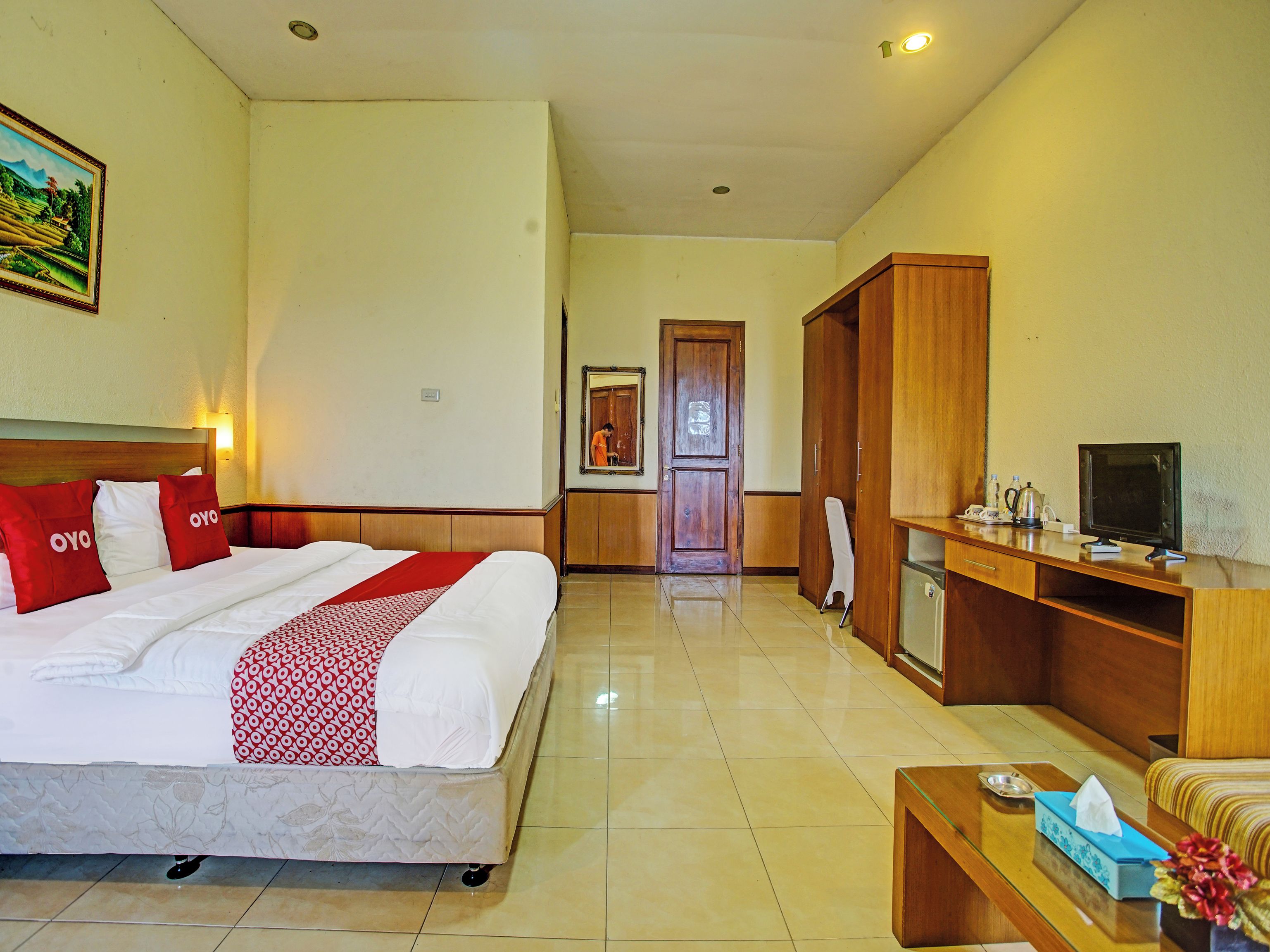 A hotel room with a bed, a desk, a television, and a bathroom visible in the background.