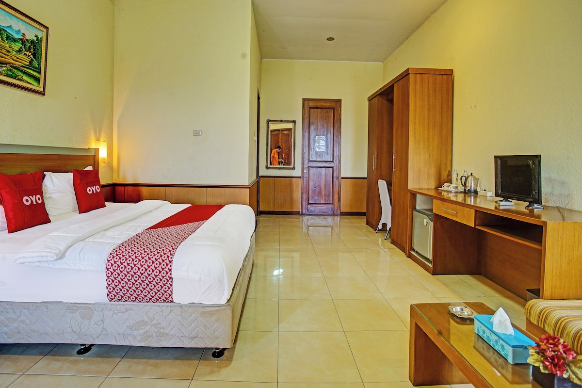 A hotel room with a bed, a desk, a television, and a bathroom visible in the background.