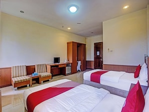A hotel room with two beds, a desk with a computer, a chair, a wardrobe, and a television. - OYO 90947 Hotel Sarbini (Menggala)