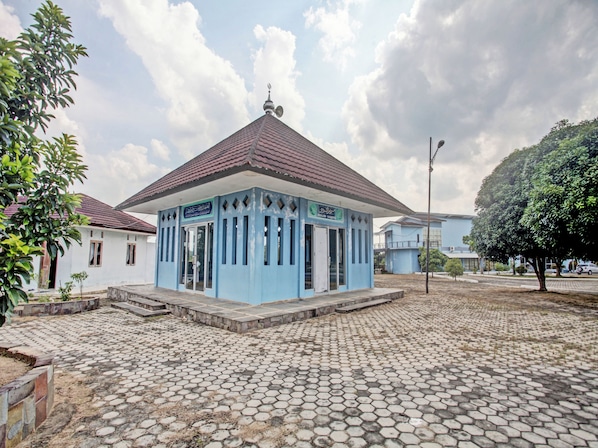 A small, single-story building with a tiled roof and a sign indicating it is a mosque. - OYO 90947 Hotel Sarbini (Menggala)