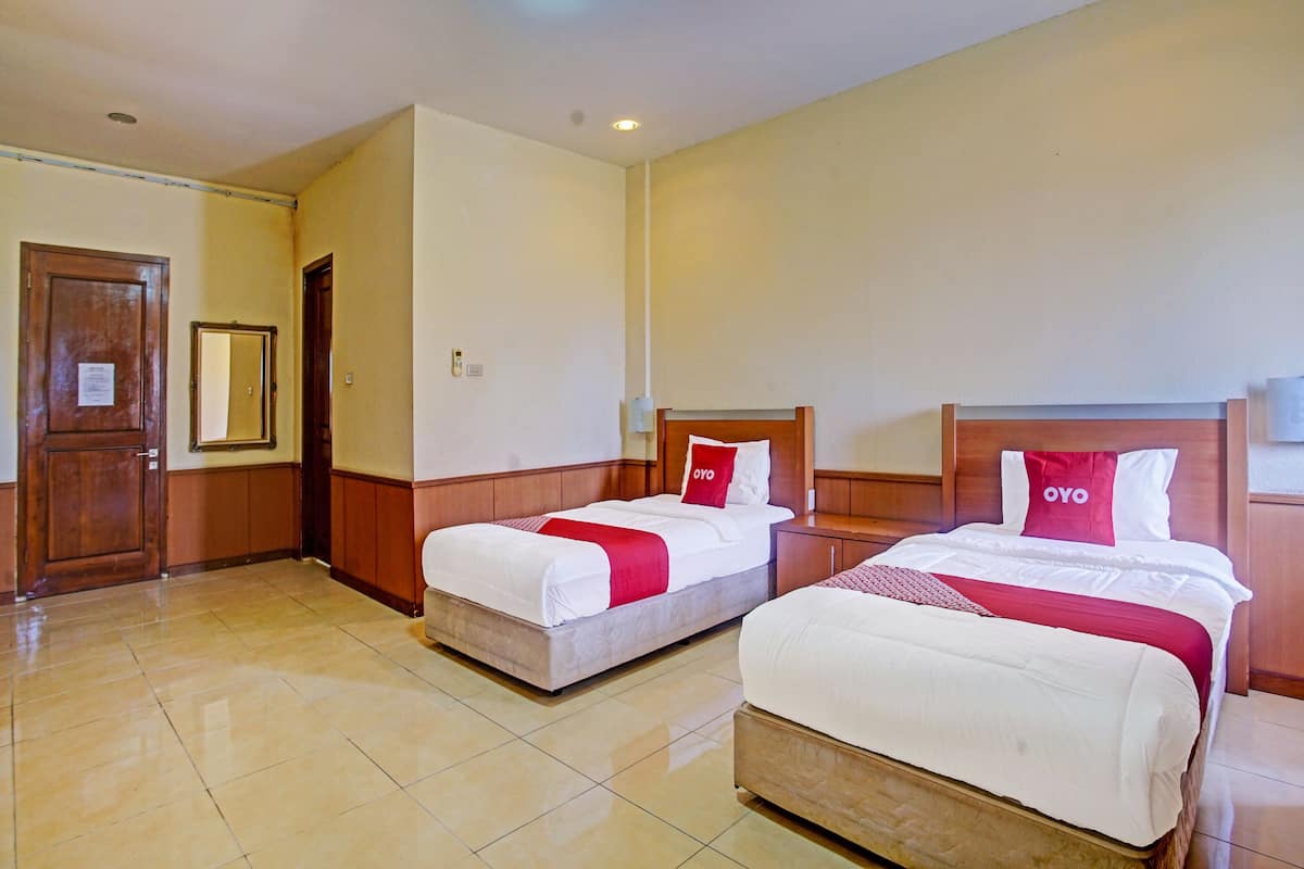 A hotel room with two beds, wooden headboards, and a tiled floor.
