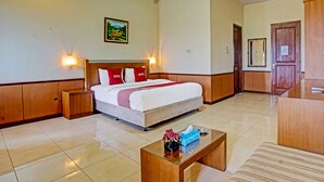 Une chambre d’hôtel comprenant un lit, des tables de chevet, une table basse, un canapé, une armoire en bois et une porte.