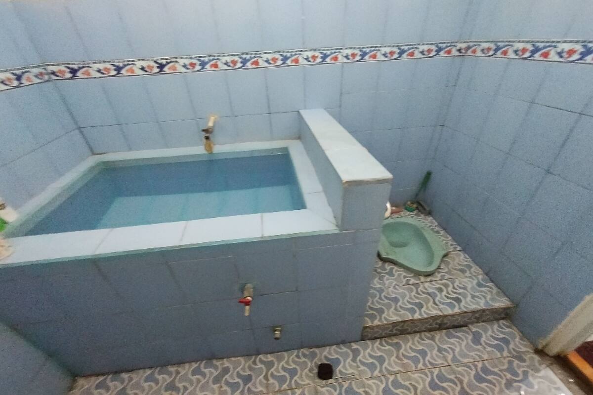 Une petite salle de bain avec une baignoire, des toilettes et des carreaux de sol à motifs.