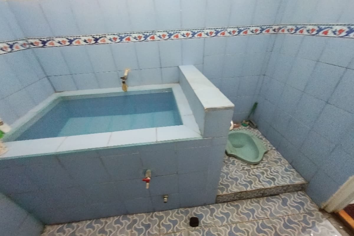 A small bathroom with a bathtub, a toilet, and patterned floor tiles.
