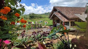 A rustic house with a tiled roof, surrounded by lush greenery and a small pond. - OYO Home 91250 Desa Wisata Taraju (Taraju)