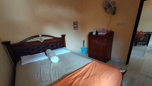 A bedroom with a bed, a wooden headboard, a nightstand, a wardrobe, and a wall-mounted fan. - OYO Home 91250 Desa Wisata Taraju (Taraju)