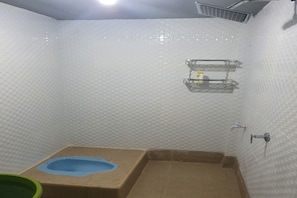 Une petite salle de bain comprenant des toilettes, une douche et une étagère avec des articles de toilette.
