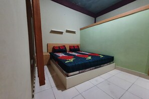 Un dormitorio con cama, mesita de noche y estante fijado a la pared.