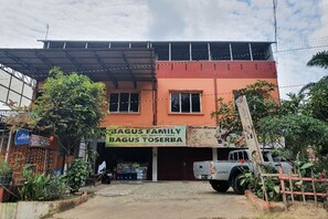 Un bâtiment à deux étages avec une enseigne indiquant « BAGUS FAMILY BAGUS TOSERBA ».