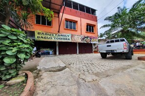 Un bâtiment sur lequel on peut lire l’inscription « BAGUS FAMILY BAGUS TESERBA » et un camion garé devant.