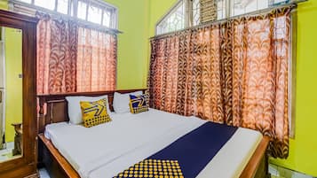 A bed with a patterned bedspread, a wooden headboard, and multiple pillows.