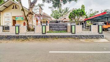 A gated entrance with a sign indicating a residential area, a covered parking area, and a building with multiple signs.