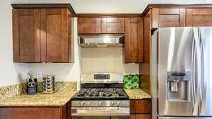 A kitchen with wooden cabinets, a stainless steel stove, and a refrigerator.
