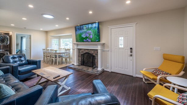 A living room with a fireplace, leather sofas, a yellow armchair, and a flat-screen TV mounted above the fireplace.
