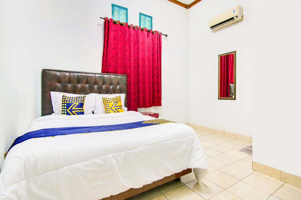 A neatly made bed with a white and blue bedspread, a brown headboard, and decorative pillows.