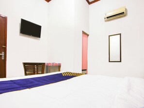 A hotel room with a bed, a television mounted on the wall, an air conditioning unit, and a mirror. - OYO 91063 Kost Bunga (Palembang)