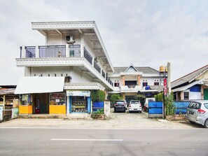 Um edifício com vários andares, varanda, um refrigerador Coca-Cola e uma loja com artigos coloridos.