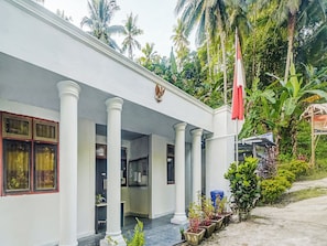 A building with a covered entrance, columns, and a flag. - OYO Homes 91118 Homesstay Desa Wisata Budo (Wori)
