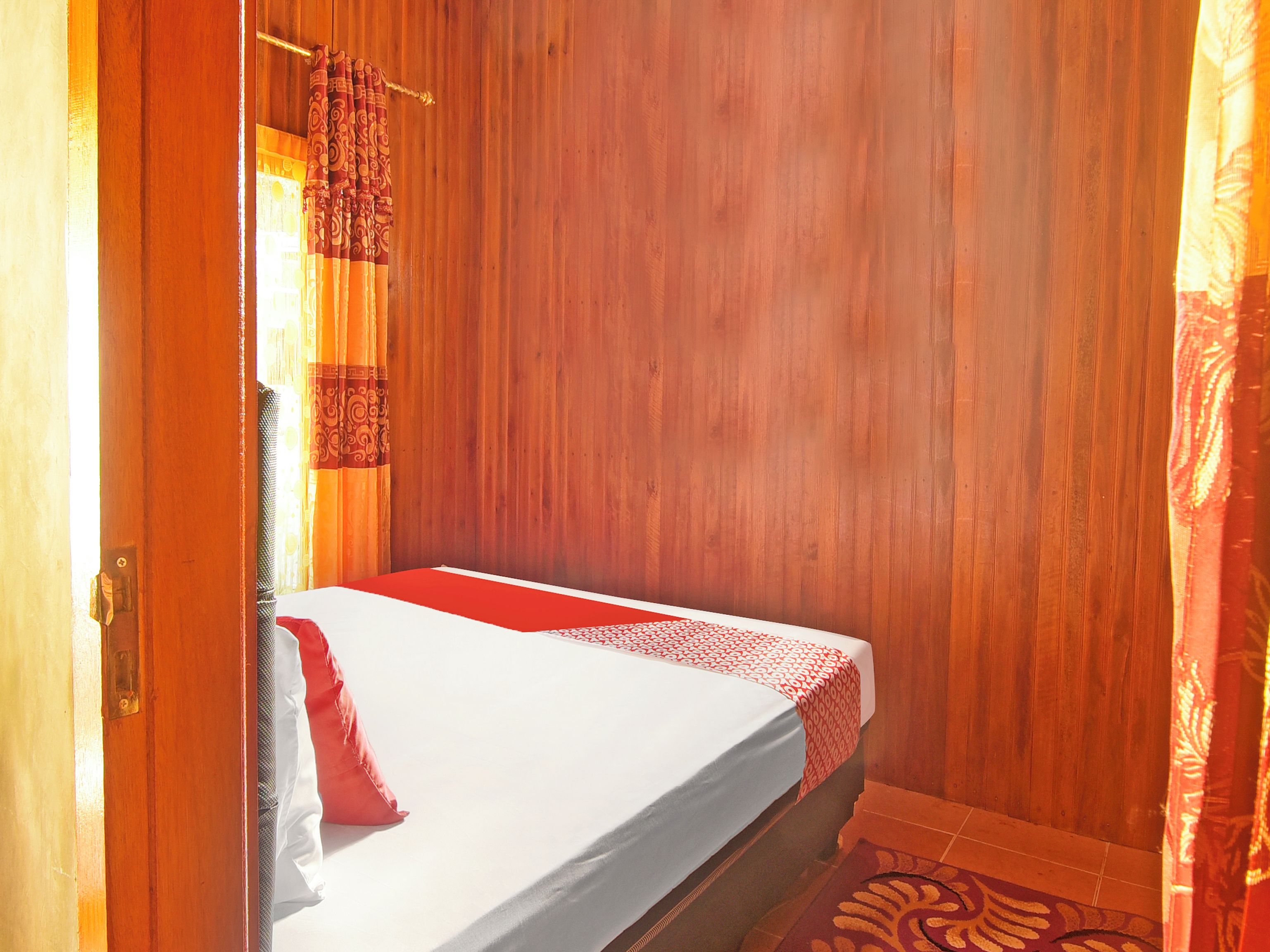 Una cama individual con colcha estampada, pared de madera y una alfombra con diseño en el suelo.