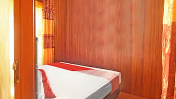 Una cama individual con colcha estampada, pared de madera y una alfombra con diseño en el suelo.